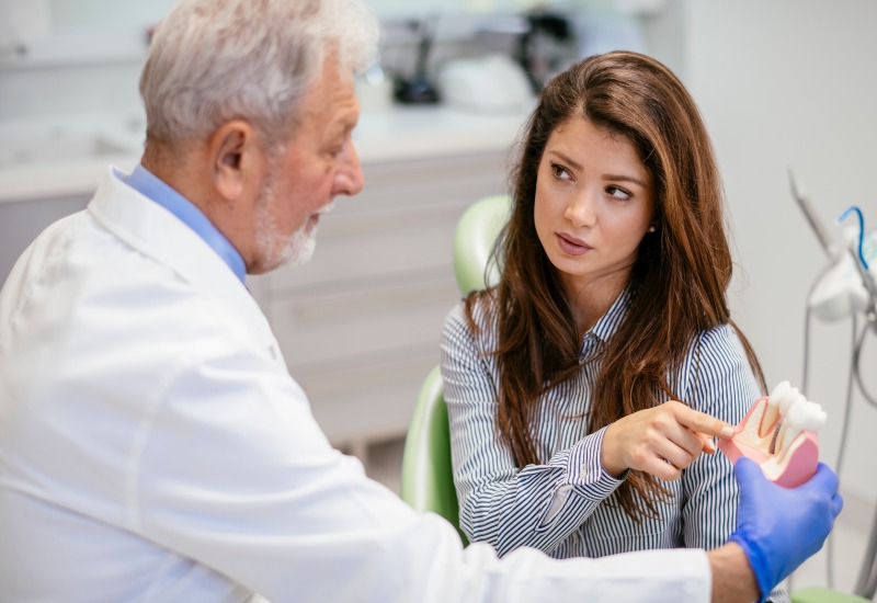 Dentist showing dental implants model to patient during consultation session in Livonia, MI
