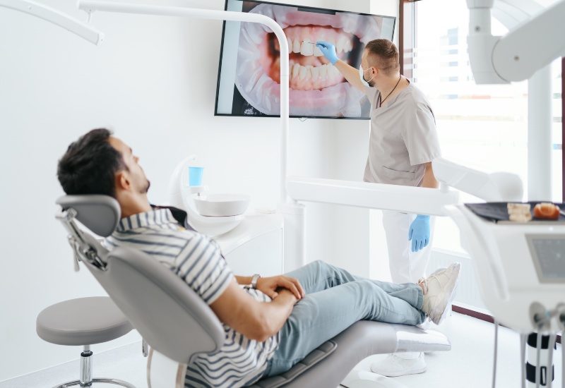 A dentist explaining a dental condition on screen to a patient in Livonia, MI