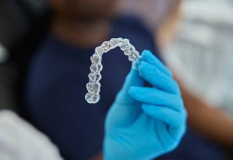 Clear aligner held by dentist in Livonia, MI