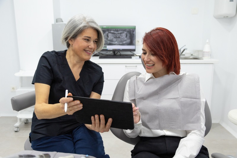 Dental professional reviews treatment plan with patient in clinic in Livonia, MI