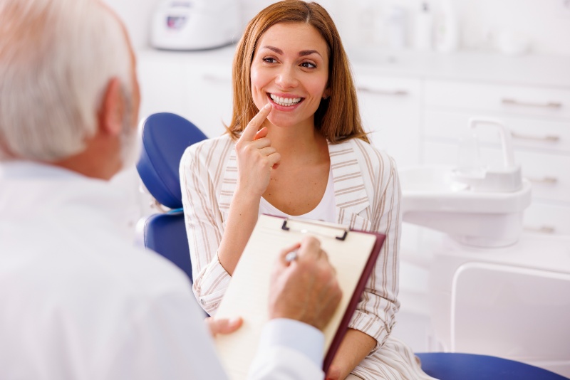 Patient consults dentist about maintaining veneers and oral health in Livonia, MI