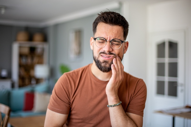 Person experiencing tooth abscess pain at home before dental visit in Livonia, MI